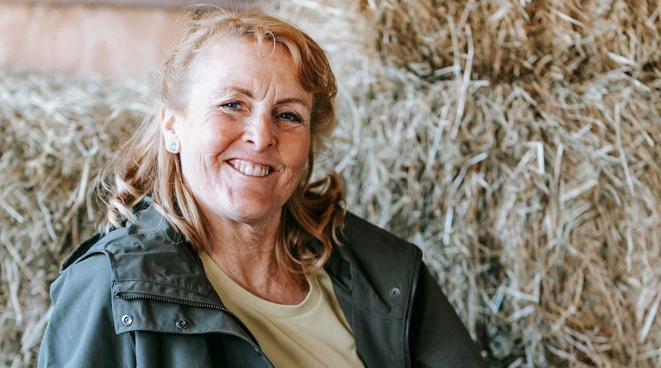 Leende kvinna vid höbalar.